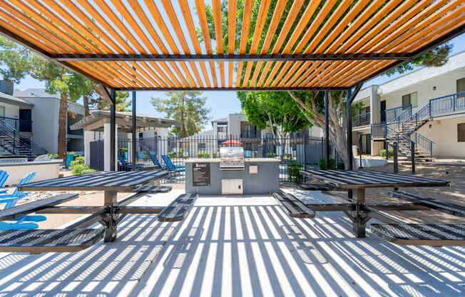 A playground with a striped pattern on the ground and a striped awning overhead.