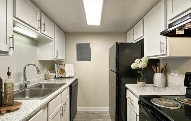 A kitchen with a black refrigerator and white cabinets.