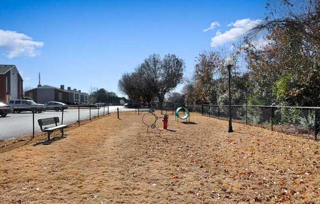 A park with a bench, a fire hydrant, and a basketball hoop.