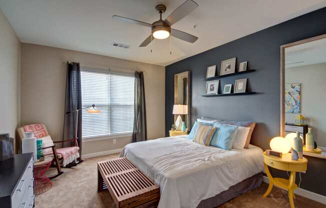 Bedroom with a bed, carpet, dresser, nightstands, and a large window.