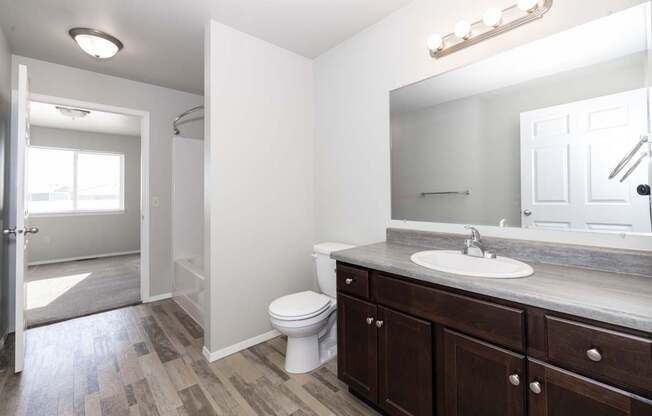 A bathroom with a white toilet, brown cabinets, and a large mirror.