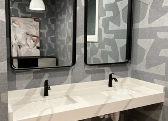 a bathroom with a gray and white wallpaper and two mirrors