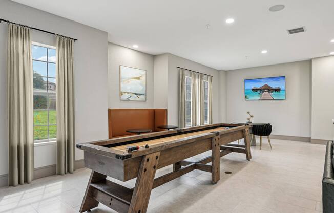 A pool table in a room with a television on the wall.