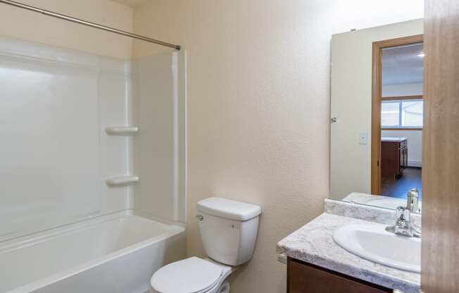 a bathroom with a sink and a toilet and a shower. Fargo, ND Westwood Apartments