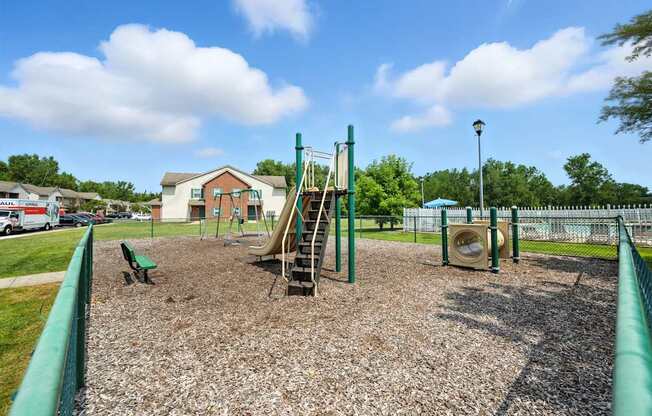 A playground with a green slide and a brown sandbox at Arbors at Georgetown Apartments, Lansing