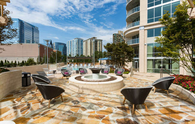 an outdoor patio with a firepit and lounge chairs with a city skyline in the background