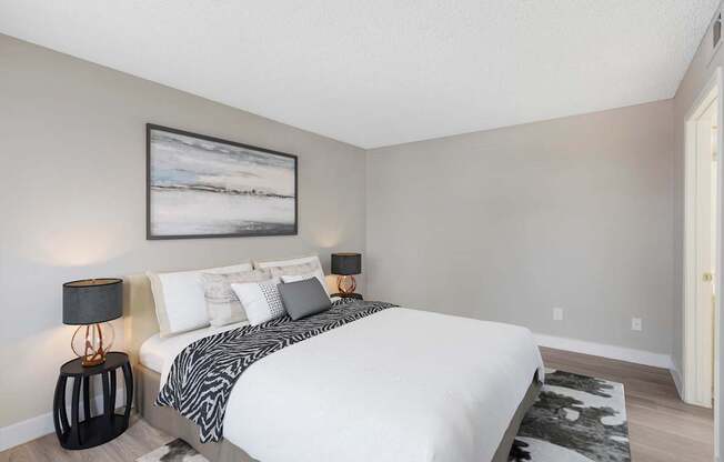 A bedroom with a large bed and a painting on the wall.