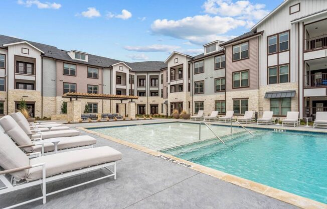 an apartment building with a swimming pool and lounge chairs