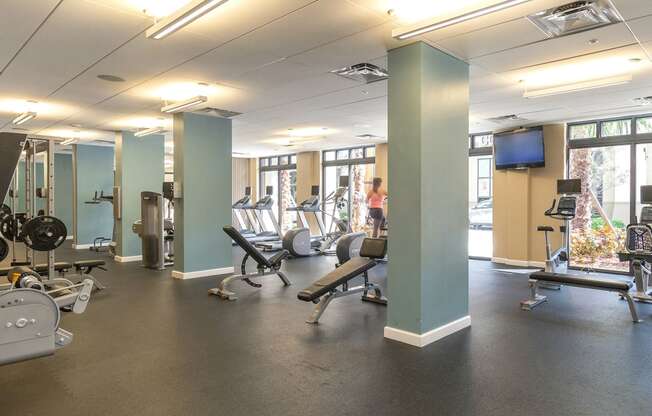 Fitness center with weight benches, weight machines, treadmills, ellipticals, stationary bikes, a television and floor to ceiling windows