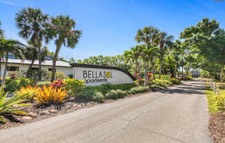 A road leading to a sign that says Bellas Apartments.