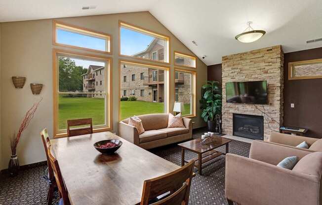 A living room with a stone fireplace and a dining table.