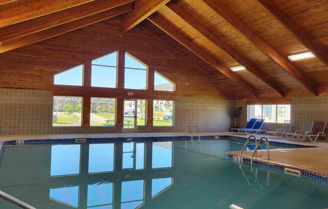 the indoor pool of a resort with a wooden ceiling and glass windows