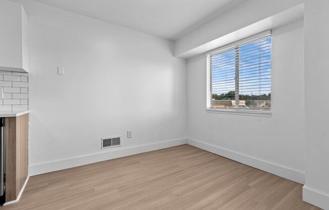 an empty living room with a window and wood flooring