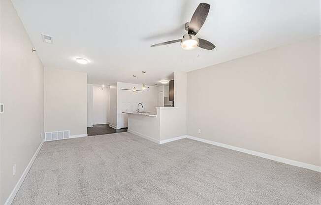 A room with a ceiling fan and carpeted floor.