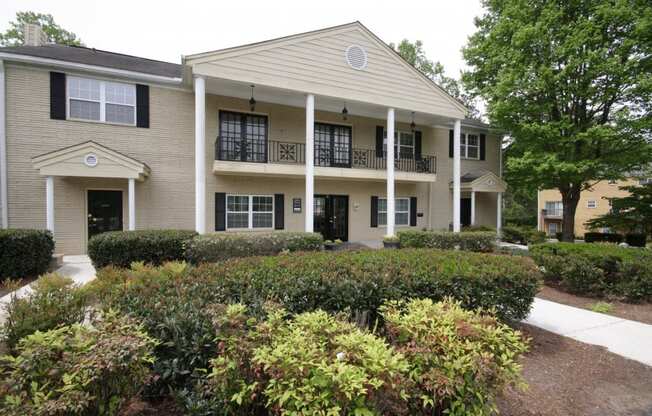 the front of a building with bushes and a sidewalk