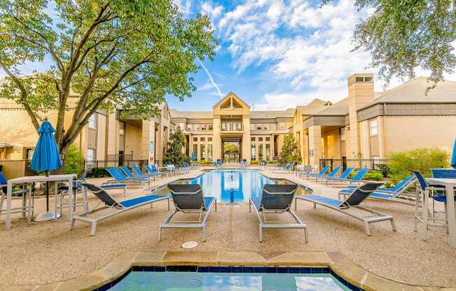 a swimming pool with chaise lounge chairs and a building in the background