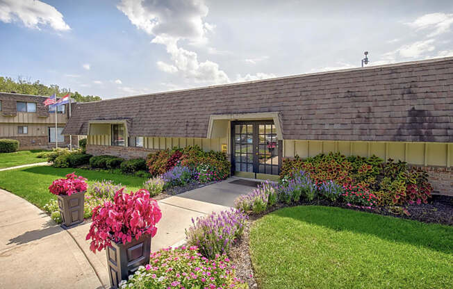 a sidewalk in front of a building with flowers and plants