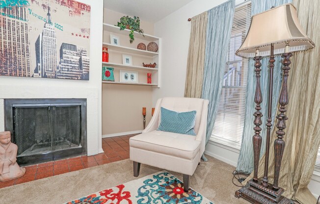 Model apartment living room with a fireplace, a chair, and a lamp at Laurel Parc apartments in Shreveport, LA.