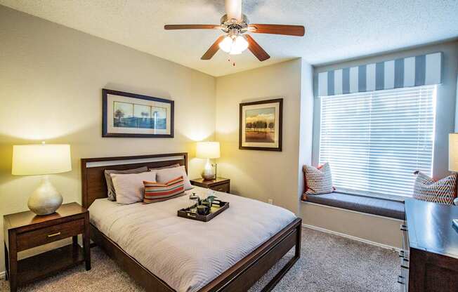 A bedroom with a bed, nightstand, and window seat.