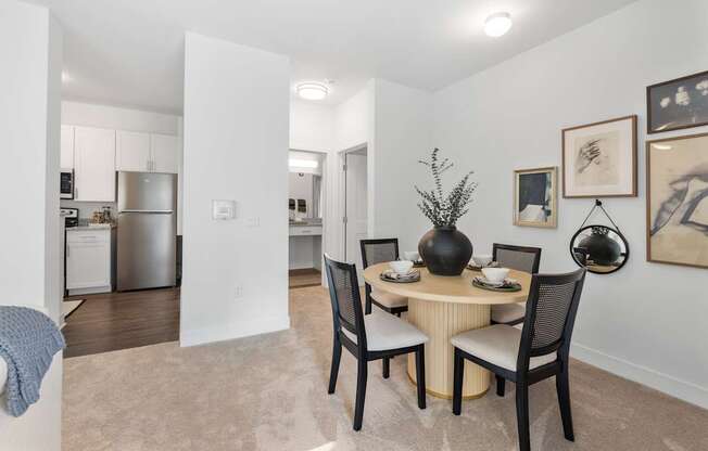 A dining room with a table set for two and a vase on the table.