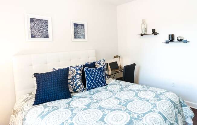 a bedroom with a bed with blue and white bedding and blue pillows