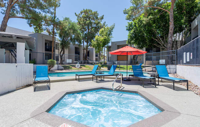 A pool with a hot tub and chairs in front of a building.