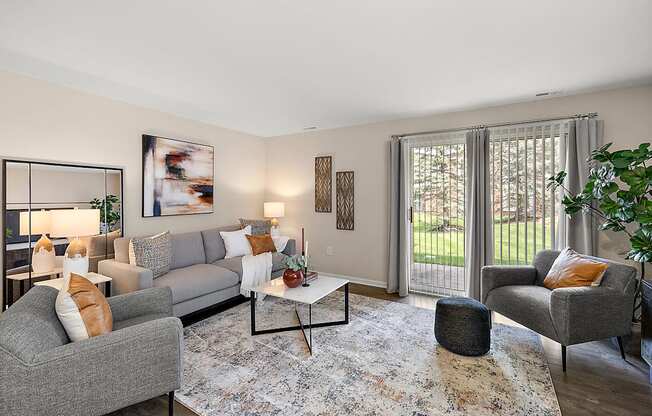 A living room with a grey couch, a grey armchair, a coffee table, and a rug.