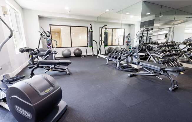 a gym with weights and other equipment on the floor and mirrored walls