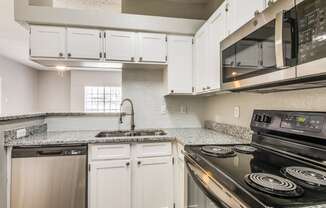 a kitchen with white cabinets and black appliances at Foxborough Apartments, Irving, TX, 75061