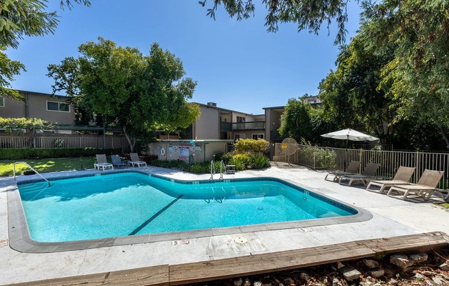 a swimming pool with chairs and a fence around it