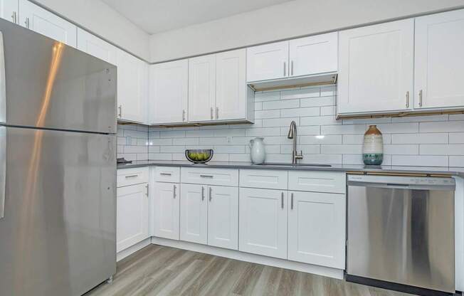 A kitchen with white cabinets and a stainless steel refrigerator.