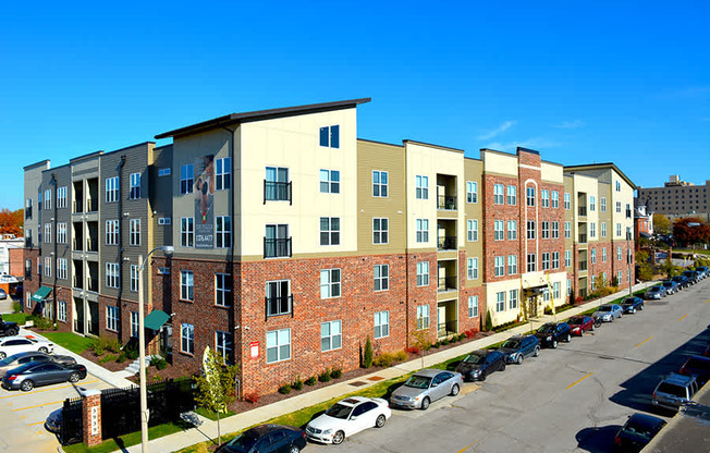 A row of apartment buildings with cars parked in front.