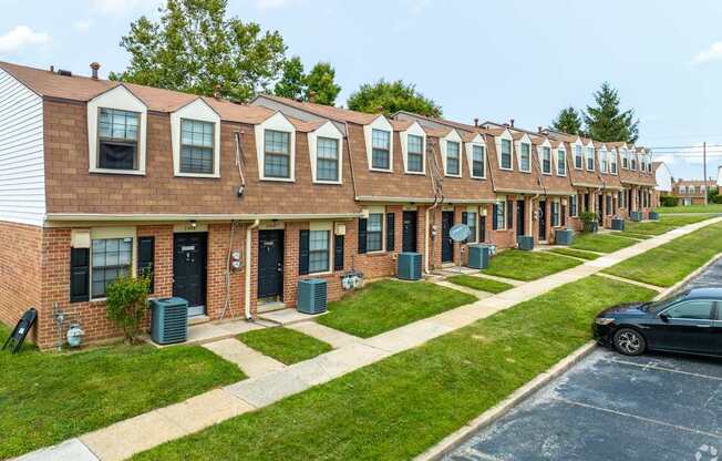 A row of red brick houses with green lawns in front.