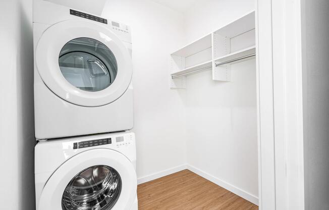 In-home laundry area with stacked washer and dryer alongside a spacious closet, designed for organized storage and everyday convenience.