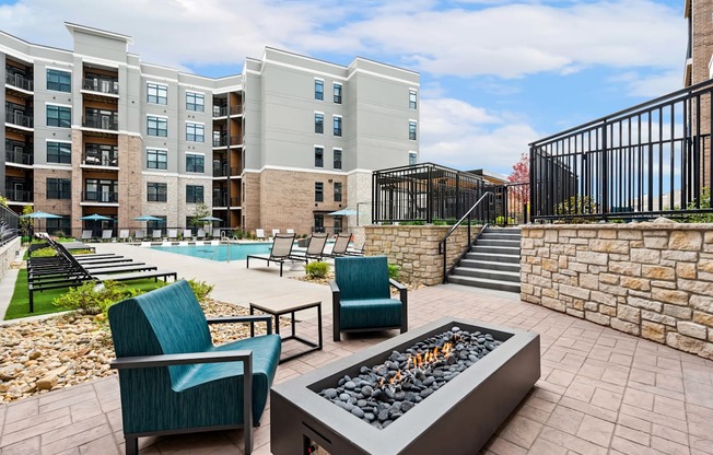 an outdoor patio with chairs and a fire pit and an apartment building