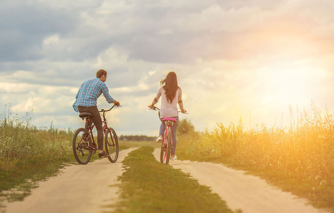 a man and a woman riding bikes down a dirt road at Brownstones at Palisade Park Townhomes, Broomfield, CO