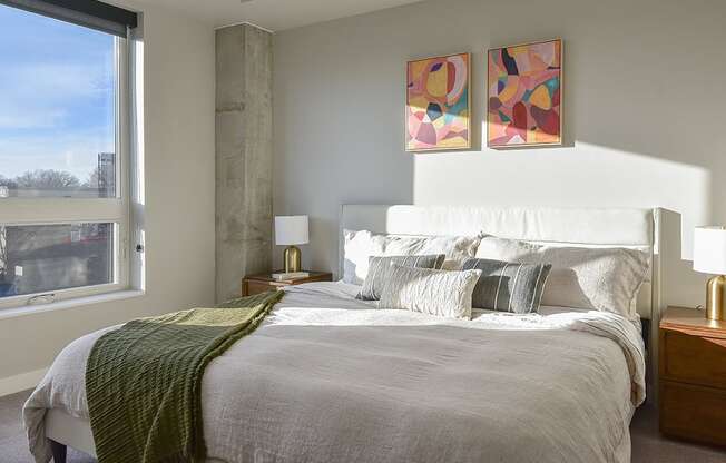 A bedroom with a large bed and two abstract paintings on the wall.