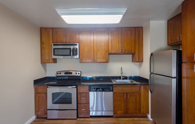 an empty kitchen with wooden cabinets and stainless steel appliances