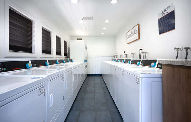 a laundry room with white washers and dryers and sinks