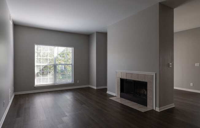 an empty living room with a fireplace and a window