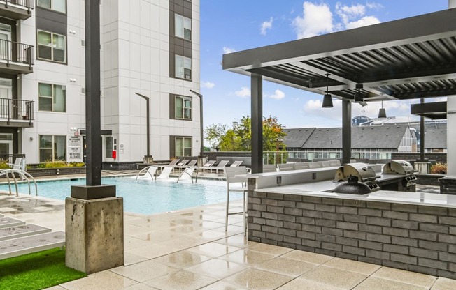 the estates at tanglewoodpool with spa and grilling area with buildings at Link Apartments® Mint Street, North Carolina