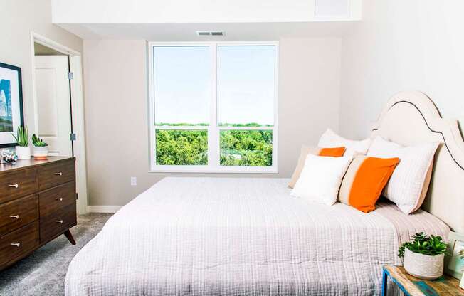 Inviting apartment bedroom with expansive nature views, featuring spacious walk-in closets and the comfort of central heating and air conditioning.