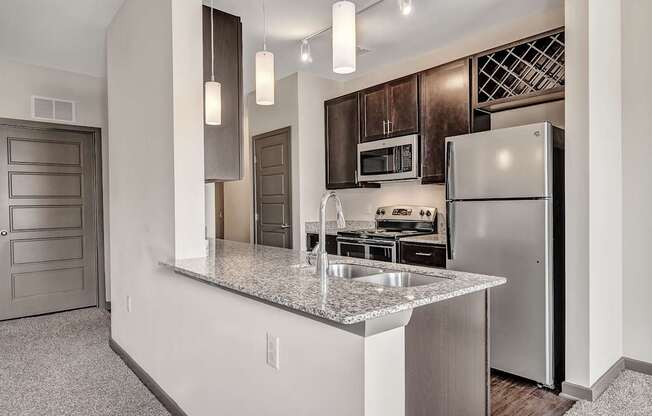 an apartment kitchen with stainless steel appliances and a granite counter top