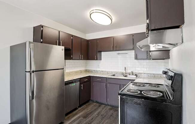 A kitchen with a stove, refrigerator, and cabinets.