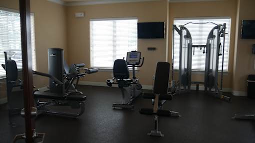 A gym with a variety of equipment including treadmills, weights, and exercise machines.