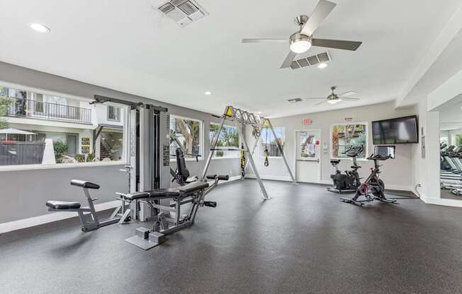 A gym with a variety of equipment including a weight bench, a treadmill, and a bicycle.