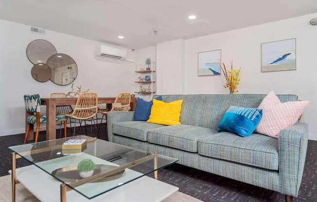 A living room with a blue couch and a glass coffee table.