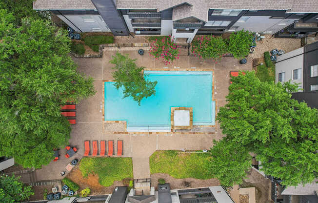 A swimming pool surrounded by trees and a building.