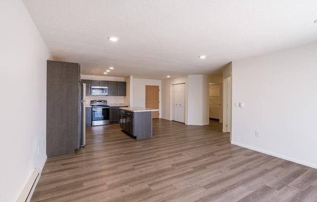 an empty living room and kitchen with wood flooring. Fargo, ND Stonebridge Apartments