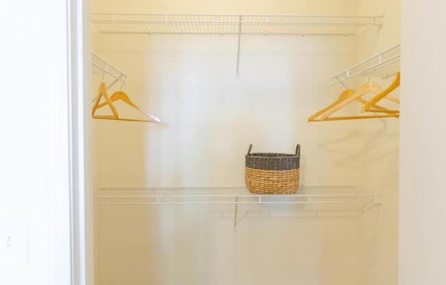 A white closet with a basket on the shelf.